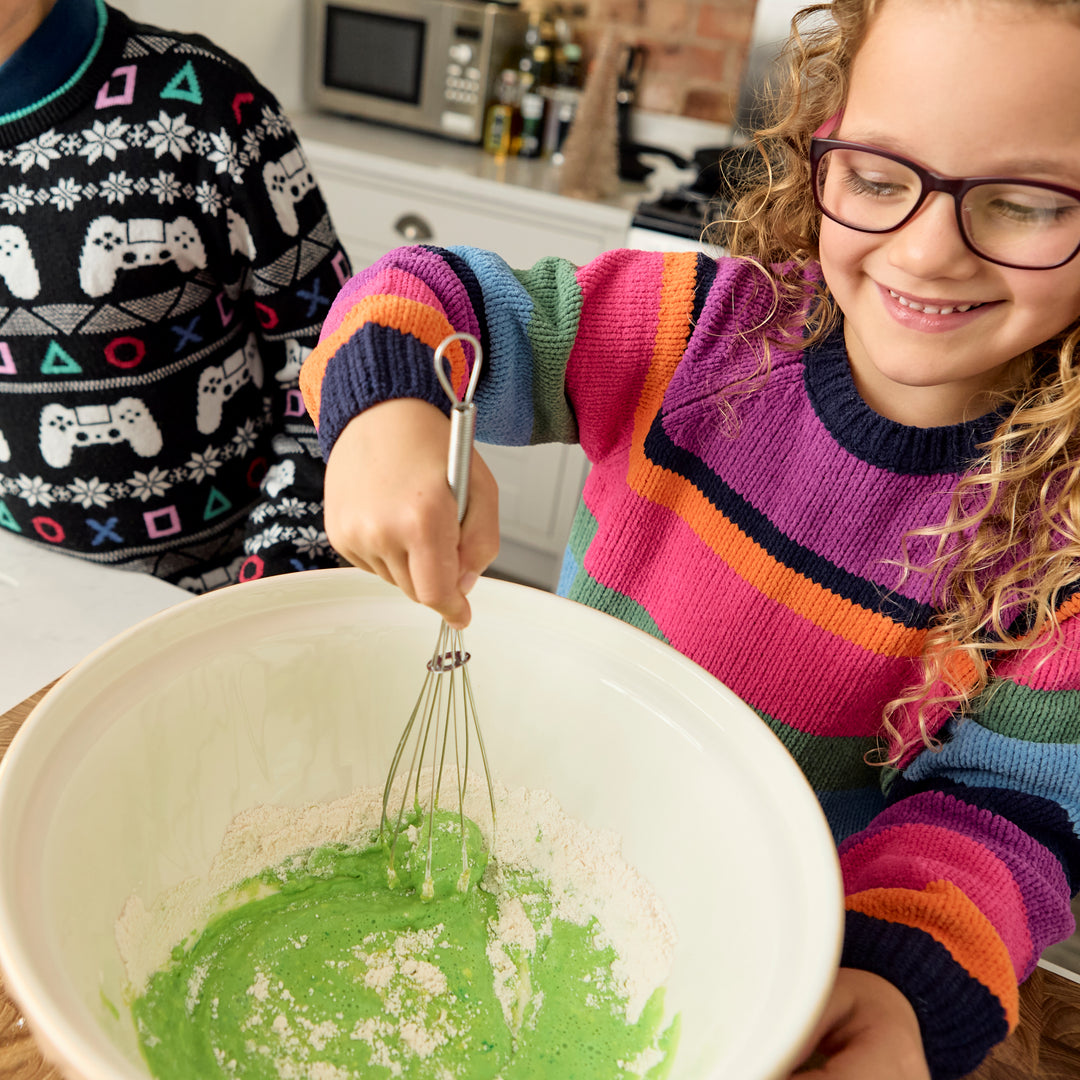 Children happily mix the Christmas Tree Pancake Mix from Stackable Pancake Co and watch the pancake mix turn festive green.